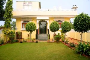 une maison jaune avec une pelouse devant elle dans l'établissement Ranthambhore Tiger Niwas, à Sawai Madhopur