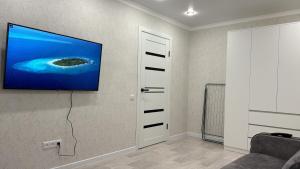 a living room with a tv hanging on a wall at Уютные 2х комнатные апартаменты на юбилейной in Uralsk