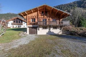 a large wooden house with a balcony on a field at Chalet de vacances Les Contamines-Montjoie in Les Contamines-Montjoie