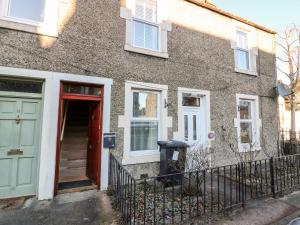 a brick house with a red door and a fence at The Wee Coorie in Peebles