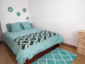 a bedroom with a bed with blue pillows and a rug at Casa dos Rosas in Melides