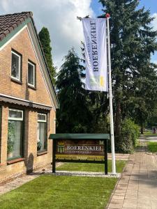 De Kiel的住宿－Boerenkiel Vakantiehuisjes，房屋前有旗帜的标志