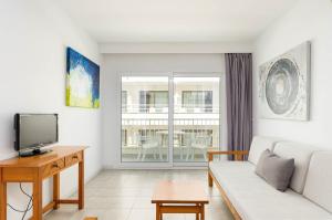 a living room with a couch and a tv at Mar Brava Apartments in Can Picafort