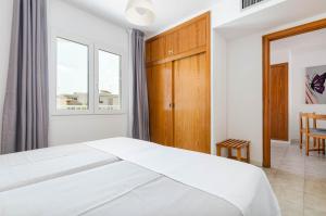 a white bedroom with a bed and a window at Mar Brava Apartments in Can Picafort