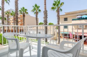 einen Tisch und Stühle auf einem Balkon mit Palmen in der Unterkunft Mar Brava Apartments in Can Picafort