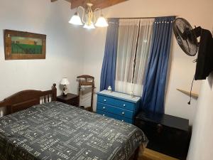 a bedroom with a bed and a blue dresser and a window at Santa Teresita en el monte in Santa Teresita