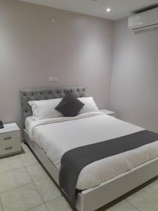 a white bedroom with a large bed and a night stand at HOTEL LAVAL in Abidjan