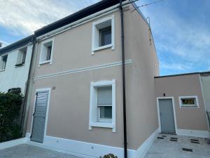 a white building with two windows and a door at Due Di Tutto in Ferrara