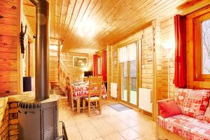 una sala de estar con una cabaña de madera con estufa de leña en Le Chant de la Rivière - Chalet 3 étoiles pour 8 personnes, en Ventron