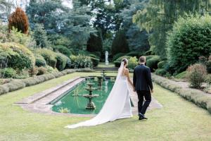 Una novia y un novio caminando por un jardín en Royal Berkshire, en Ascot