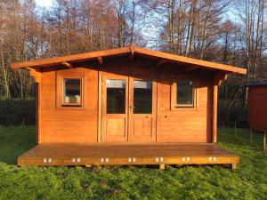 a wooden cabin with a porch in the grass at X Adventure in Horsford