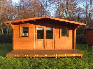 a wooden cabin with a porch in the grass at X Adventure in Horsford +11 photos