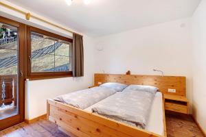 1 dormitorio con cama de madera y ventana en Unterdurachhof Apartment Martin, en Ultimo