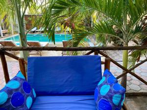 una silla azul con almohadas azules junto a la piscina en CeZeRe THE PALM HOTEL en Paje