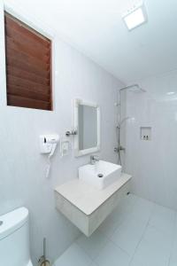 a white bathroom with a sink and a mirror at The Shark Residence in Fuvahmulah