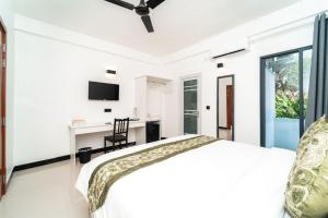 a white bedroom with a bed and a desk at The Shark Residence in Fuvahmulah
