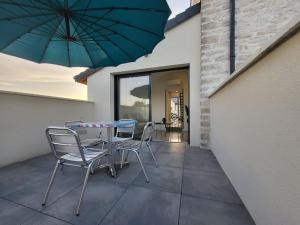 a patio with a table and chairs and an umbrella at Le cosy 2 personnes in Oslon