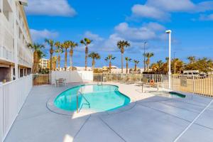 a swimming pool with a fence and palm trees at Tranquil Harbour 102 in Mexico Beach
