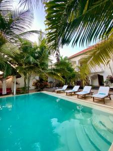 帕傑的住宿－CeZeRe THE PALM HOTEL，一个带躺椅的游泳池,棕榈树