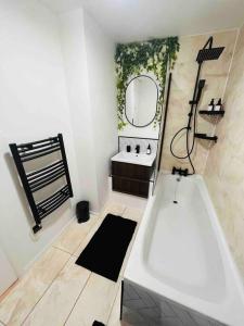 uma casa de banho com uma banheira, um lavatório e um espelho. em Hidden Oasis Comfy Studio in New Cross London em Londres