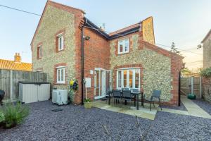 a brick house with a table and chairs in the courtyard at Victory Cottage in Little Walsingham