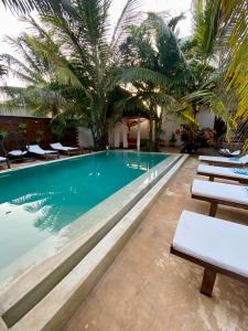 uma piscina num hotel com espreguiçadeiras e palmeiras em CeZeRe THE PALM HOTEL em Paje