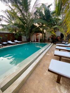 a pool at a hotel with lounge chairs and palm trees at CeZeRe THE PALM HOTEL in Paje