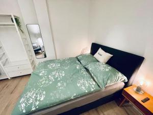 a bedroom with a bed with green sheets and a mirror at City Apartment Rudolf 26m2 in Graz