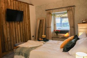 a bedroom with a bed with a television on the wall at Tanyard Barn - Luxury Hot Tub & Secure Dog Field Included in Old Glossop