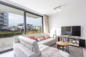 a living room with a white couch and a large window at Gezellig appartement - Zeeparel - 6 personen - 3 kamers in Middelkerke