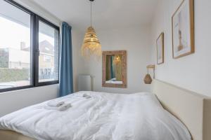 a white bedroom with a bed and a window at Gezellig appartement - Zeeparel - 6 personen - 3 kamers in Middelkerke