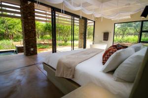 a bedroom with a large bed and large windows at Ungava Retreat in Marloth Park