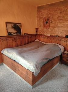 ein Holzbett in einem Zimmer mit Ziegelwand in der Unterkunft Falco und Stephanie Kirchbichler in Bad Klosterlausnitz