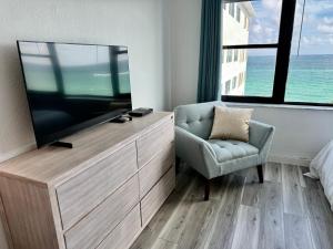 ein Schlafzimmer mit einem TV, einem Stuhl und einem Sofa in der Unterkunft Directly on the Beach with Pool & Ocean View in Miami Beach