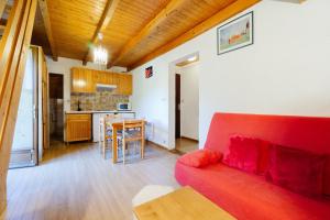 a living room with a red couch and a kitchen at Appartement 5 pers in Saint-Sorlin-dʼArves