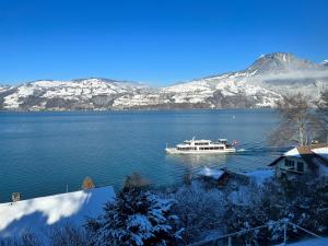 um barco num lago com montanhas cobertas de neve em Wohnung mit grossartiger Seesicht und Balkon em Spiez