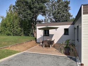 a patio with a table and an umbrella at Joli chalet contemporain, calme et verdure. in Martin-Chapon
