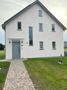 a white house with a driveway at B&B Zirbenduft in Ribnitz-Damgarten
