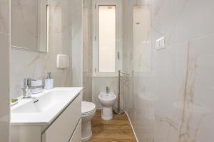 bagno bianco con lavandino e servizi igienici di Fior Di Loto Rooms a Cagliari
