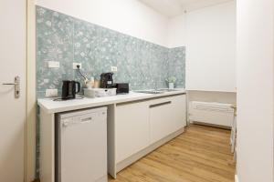 a kitchen with white cabinets and green wallpaper at Fior Di Loto Rooms in Cagliari