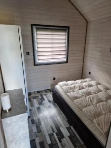 een slaapkamer met een bed in een kamer met een raam bij Domki Paradise 700m od morza !!! in Jarosławiec +4 foto's