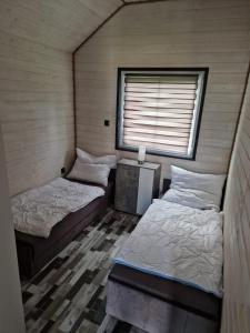 twee bedden in een kamer met een raam bij Domki Paradise 700m od morza !!! in Jarosławiec