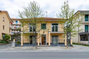 un edificio amarillo con árboles delante de él en Casa dei artisti 1, en Casarza Ligure