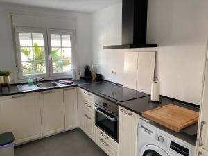 a kitchen with white cabinets and black counter tops at Villa Venna, with a private pool in Baños y Mendigo