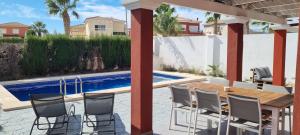 a patio with a table and chairs next to a swimming pool at Villa Venna, with a private pool in Baños y Mendigo
