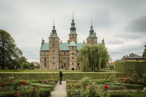 a person walking in front of a castle with flowers at Spacious 3 Bedroom Flat in Peaceful Area in Copenhagen