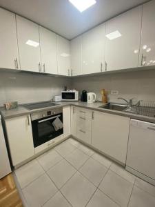 a kitchen with white cabinets and a sink and a microwave at Apartman Lux 5- private parking in Sombor