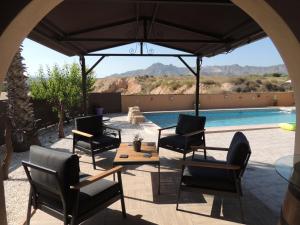 a patio with chairs and a table and a pool at The Olive Mill in La Murada