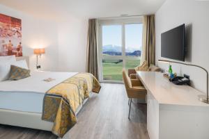 um quarto de hotel com uma cama, uma secretária e uma janela em Hotel Swiss Star em Wetzikon
