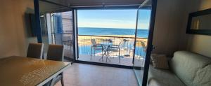 a living room with a table and a balcony with the ocean at Bella vista in L'Ametlla de Mar